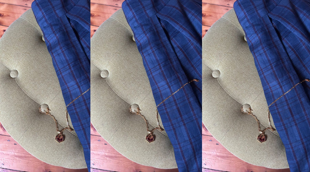navy check skirt and gold heart necklace with a dark stone, thrown over a green armchair