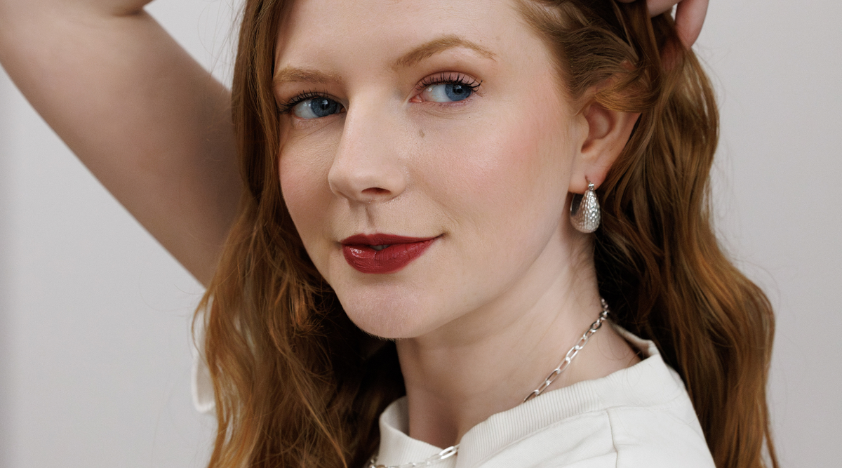 woman with red hair and lipstick wearing silver jewelry