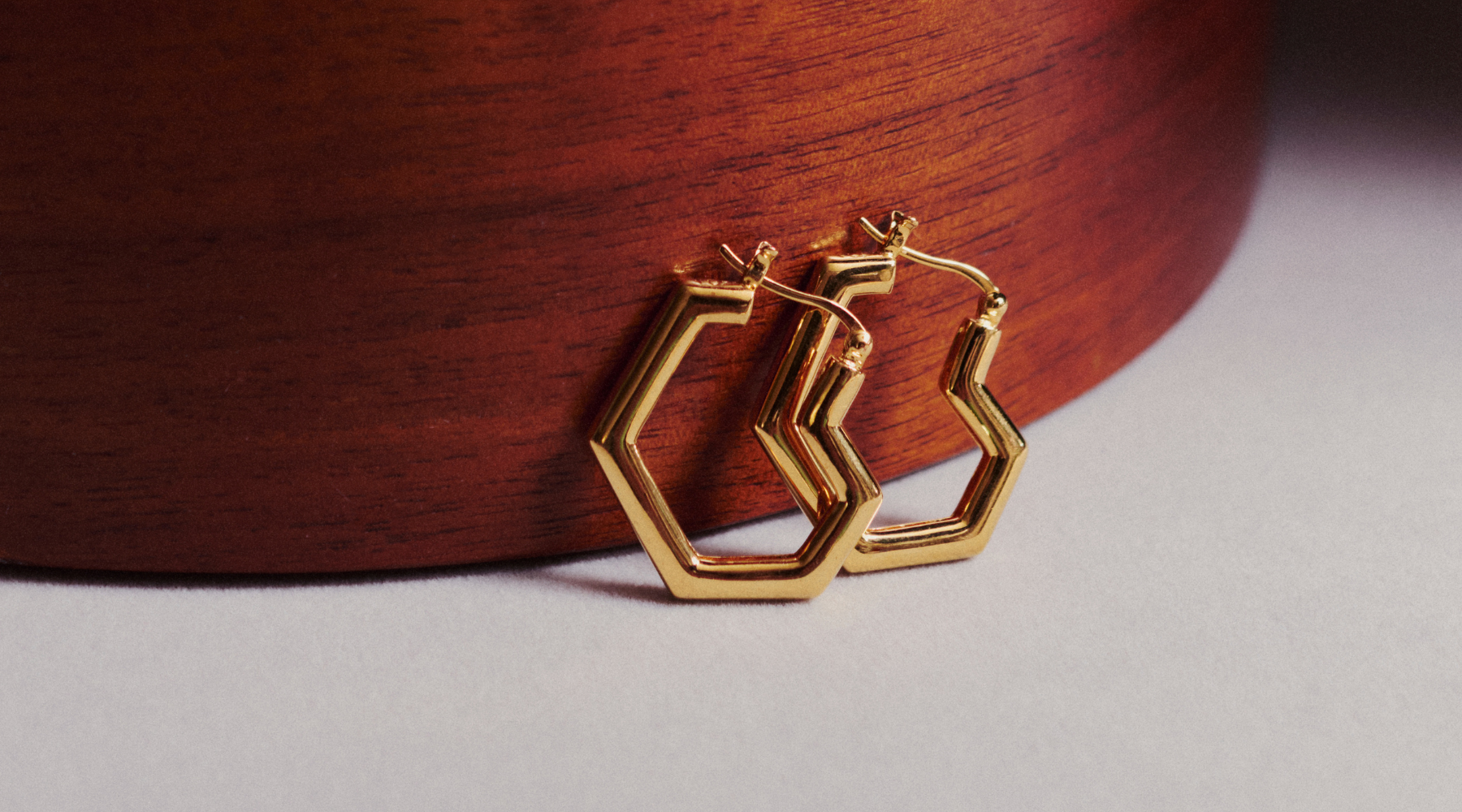 gold heart shape hoop earrings against a wooden background