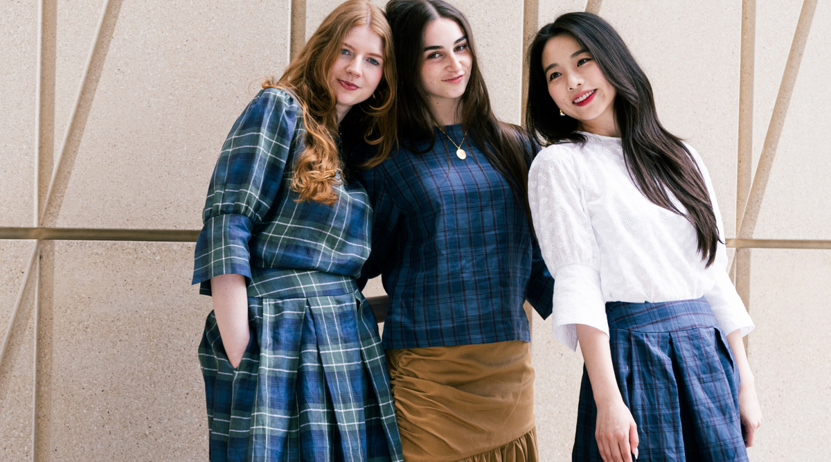 close up of three women wearing check skirts and tops