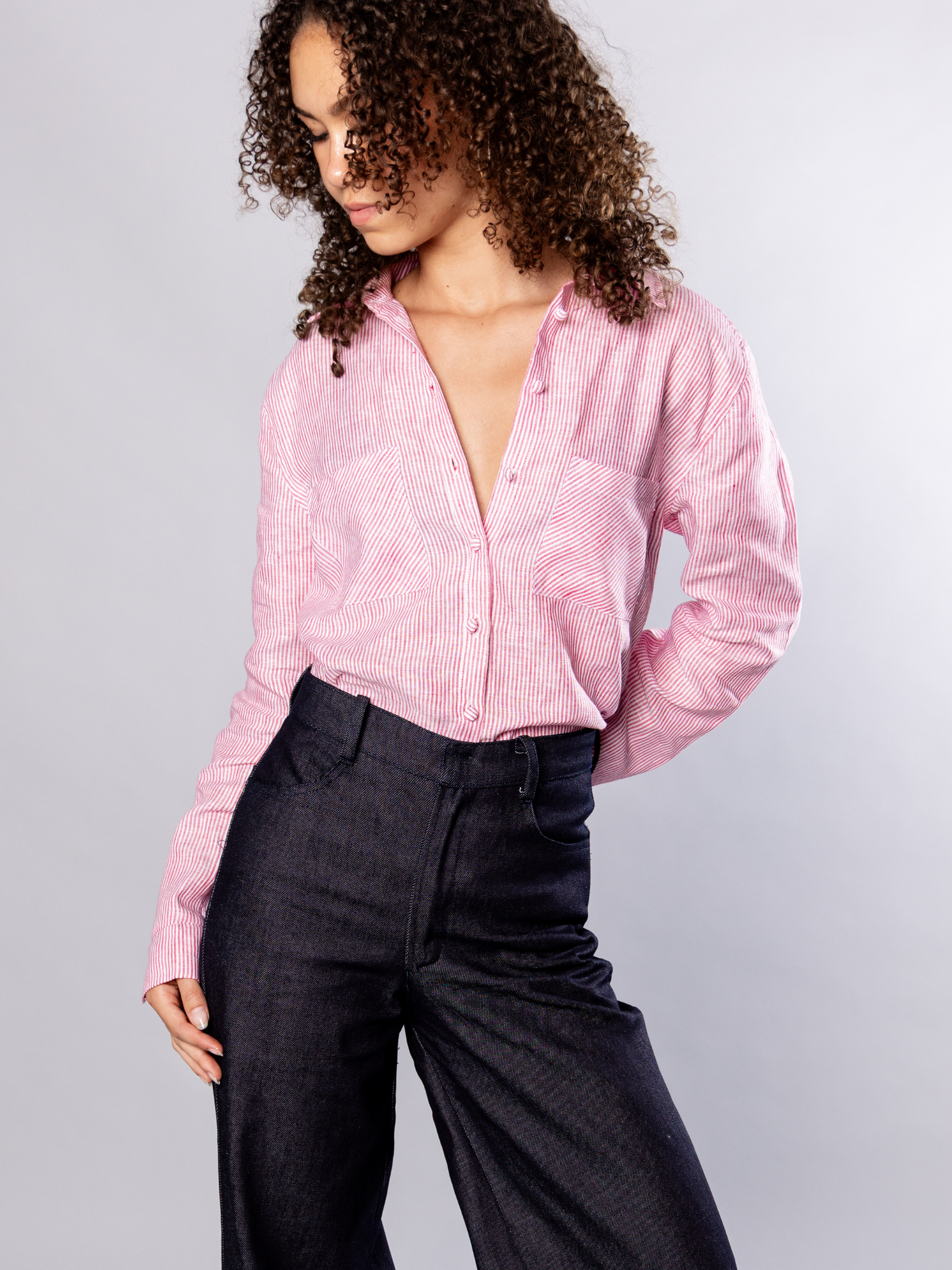 Person wearing a red stripe shirt and navy denim pants on a plain background