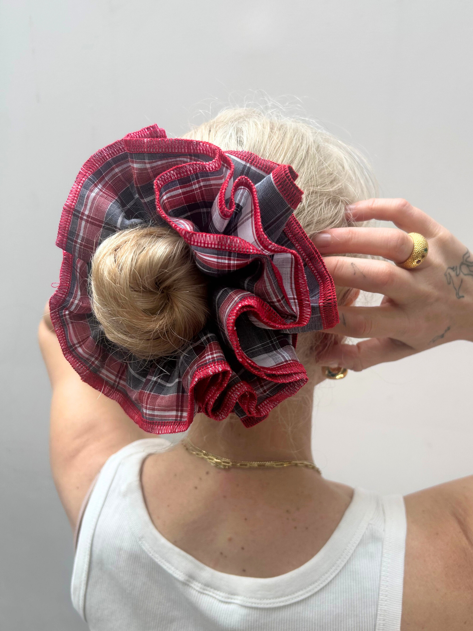 Person wearing a large red plaid scrunchie on their head against a plain background