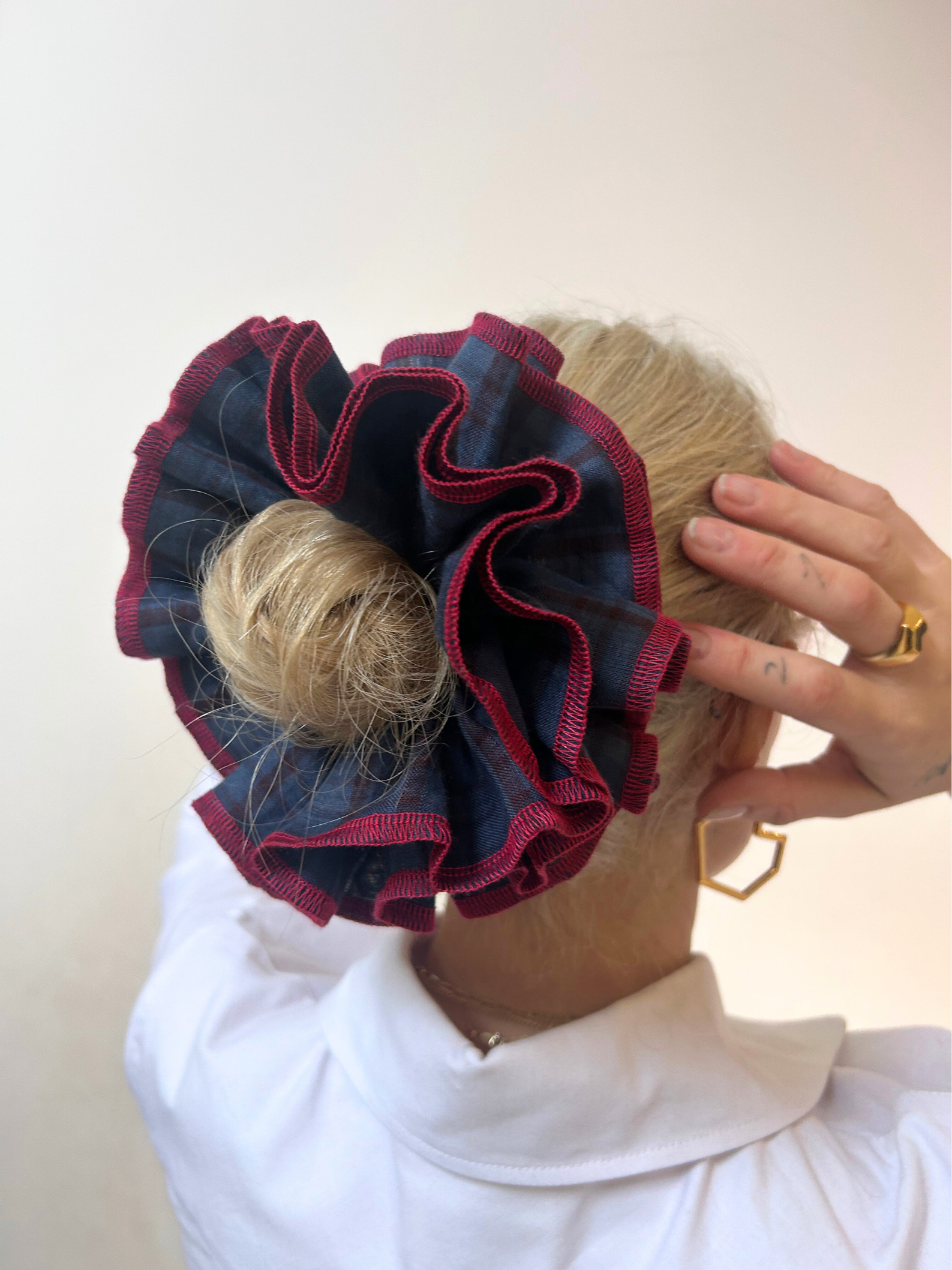 Person wearing a decorative hair scrunchie with red and blue fabric on a plain background