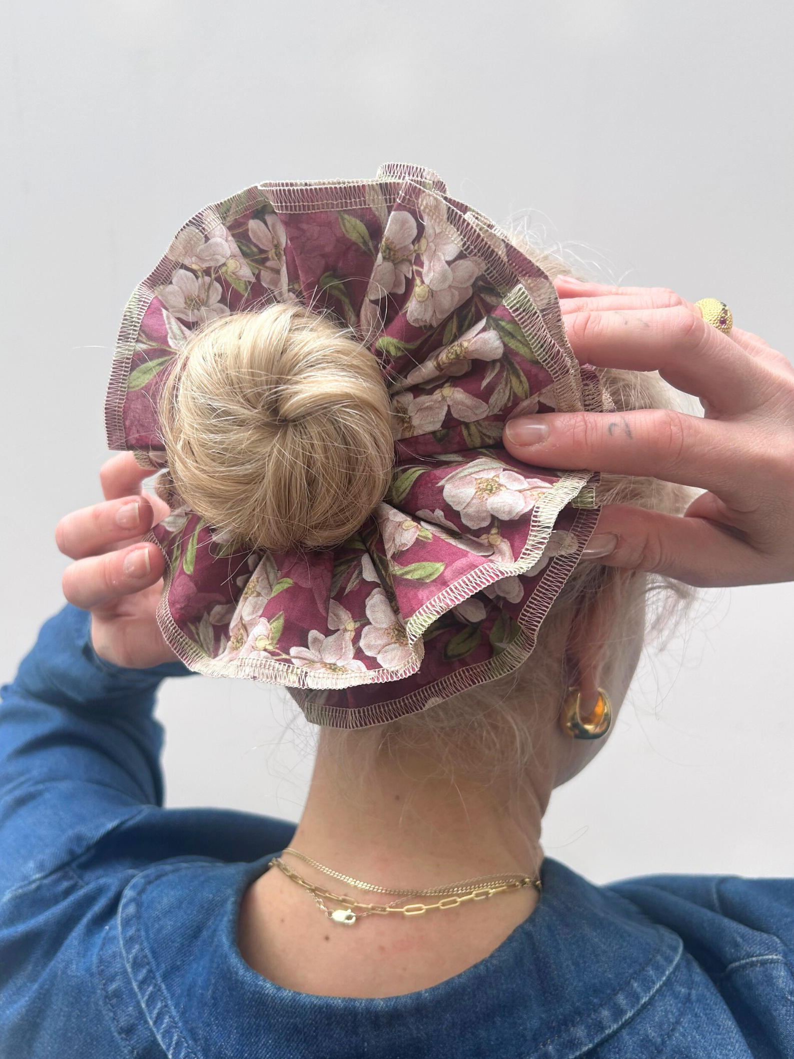 Person wearing a floral hair bun cover with a plain background