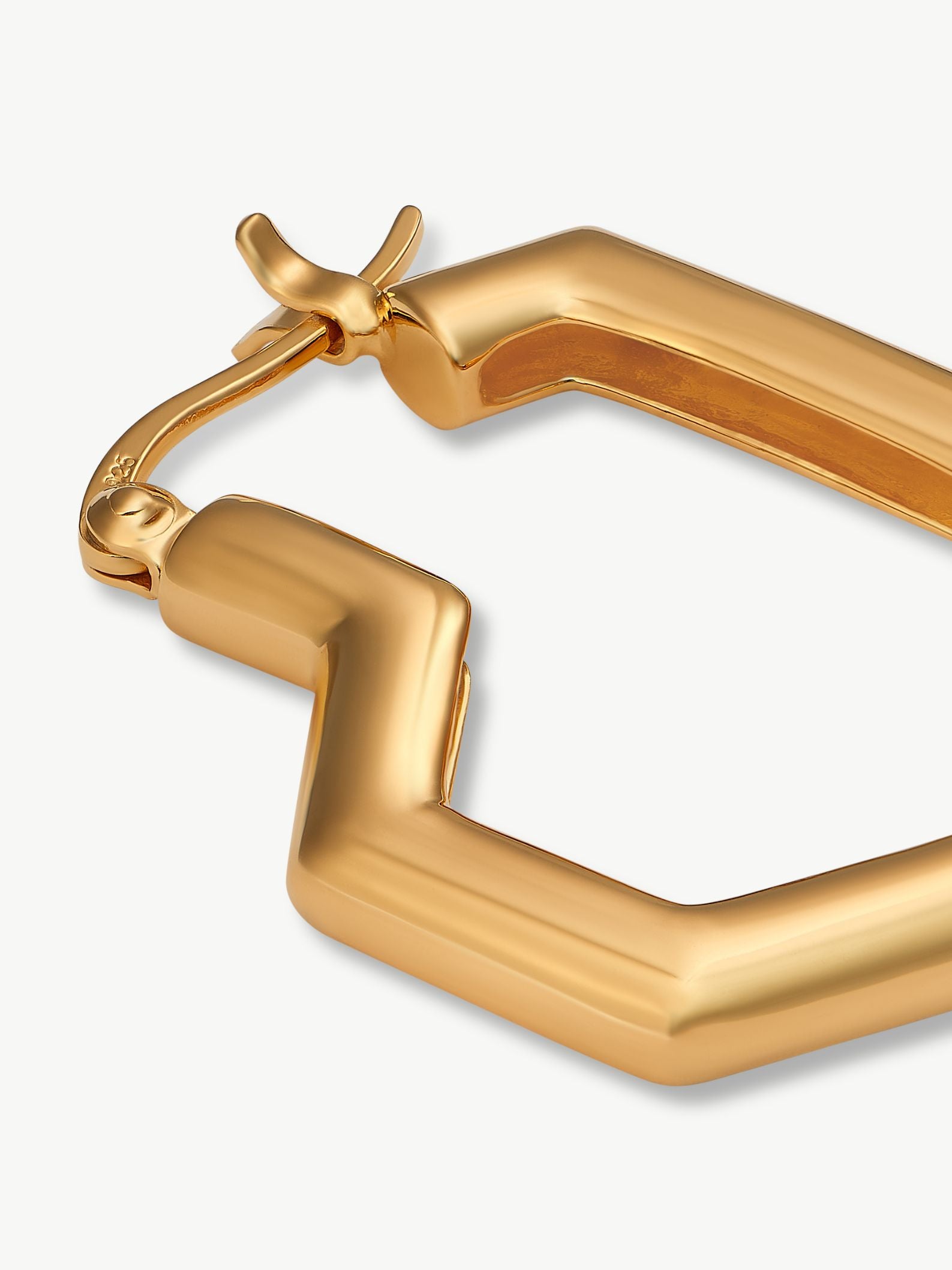 Gold hoop earring on a light grey background