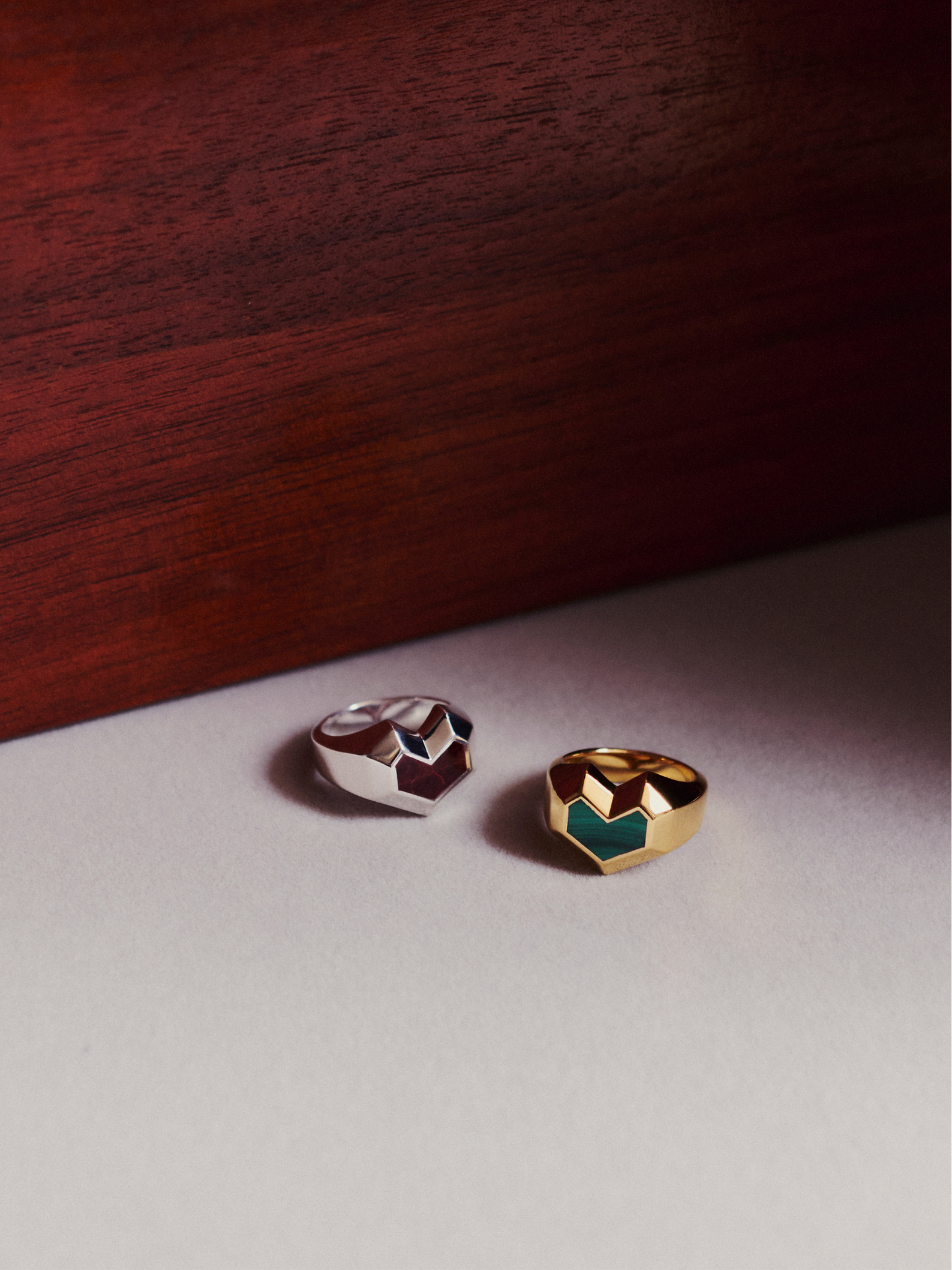 Two heart-shaped rings on a light surface with a wooden background