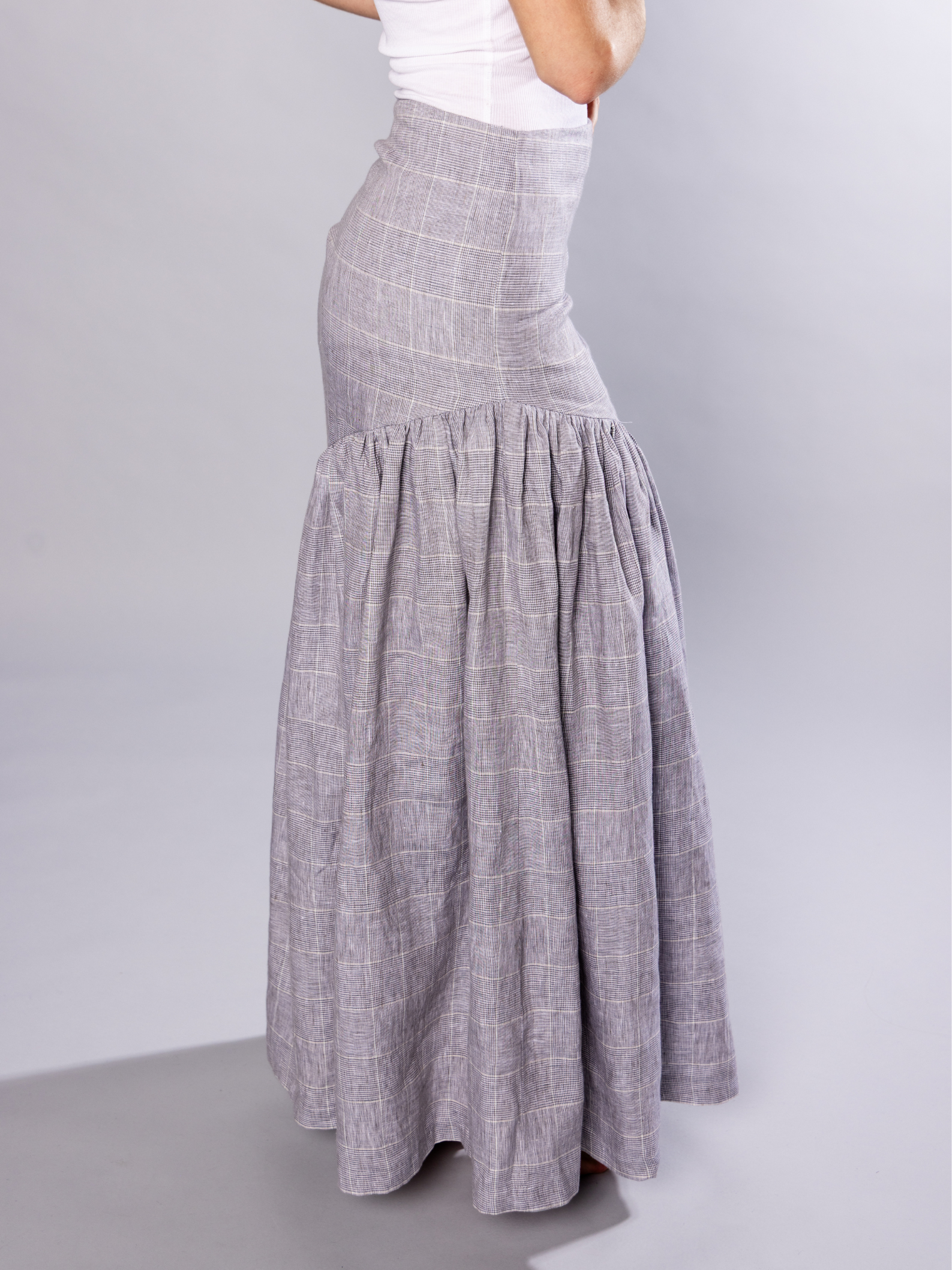 Long grey checkered gathered skirt worn by a person on a plain background