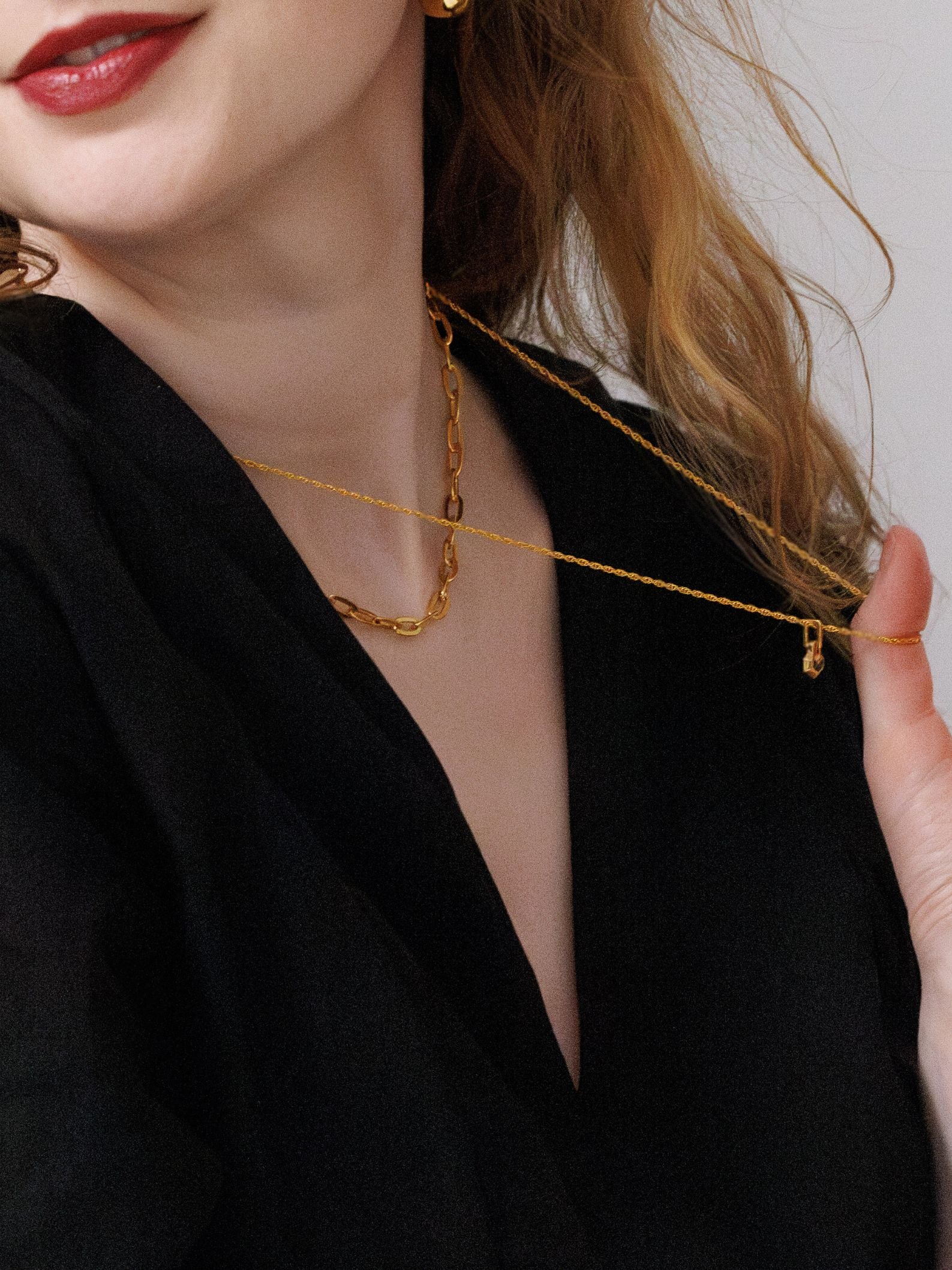 Close-up of a person wearing a gold necklaces with a plain background