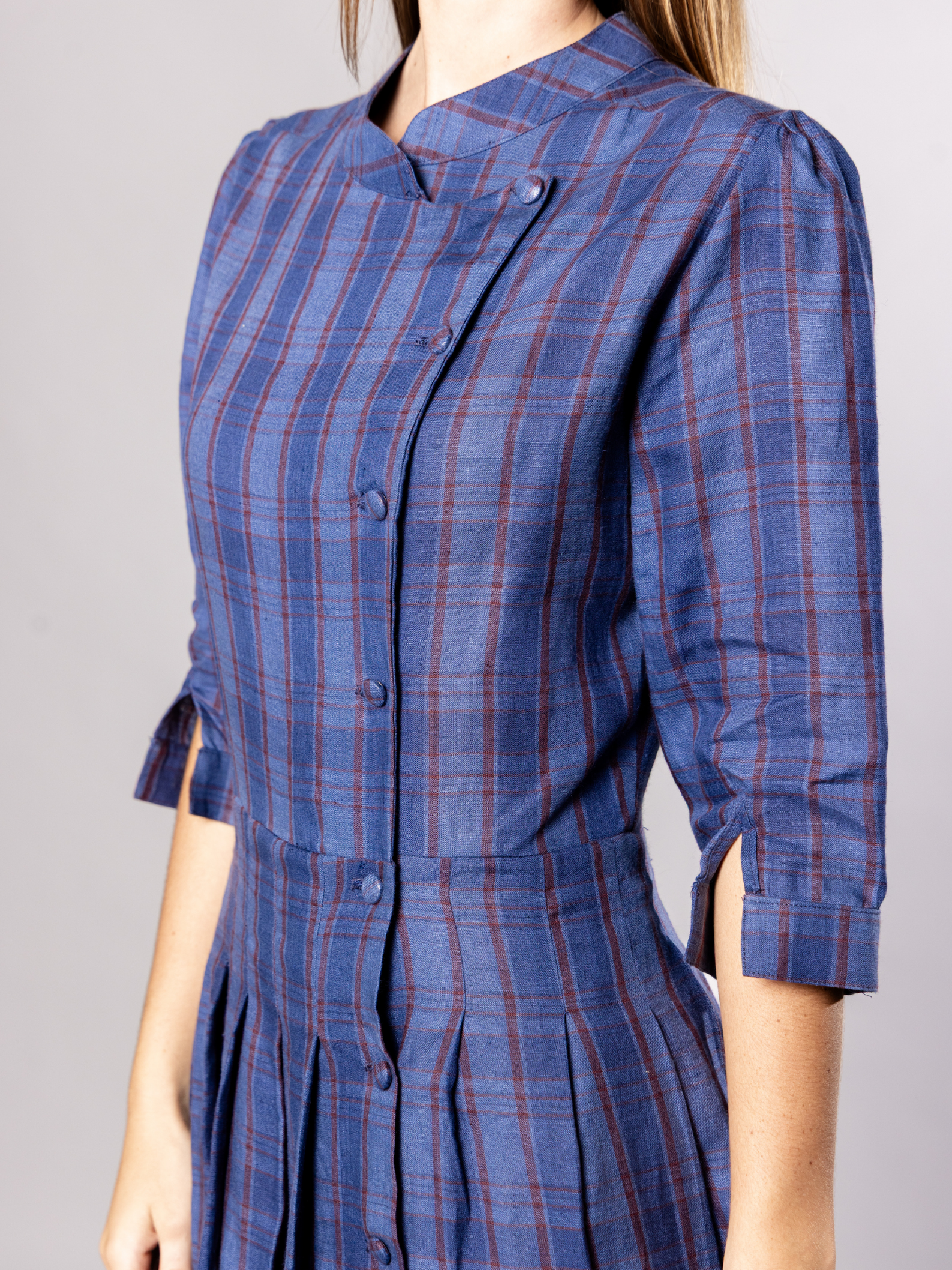 Navy blue plaid dress with side buttons worn by a person on a grey background