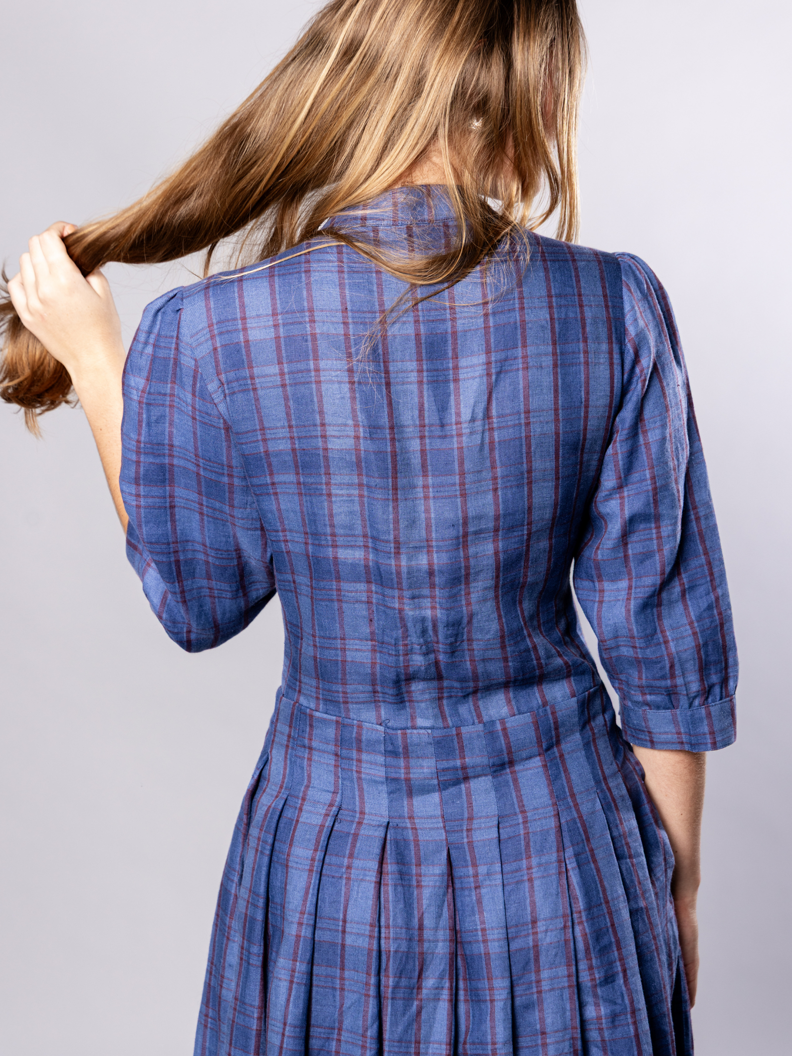 Woman wearing a navy blue plaid dress against a plain background