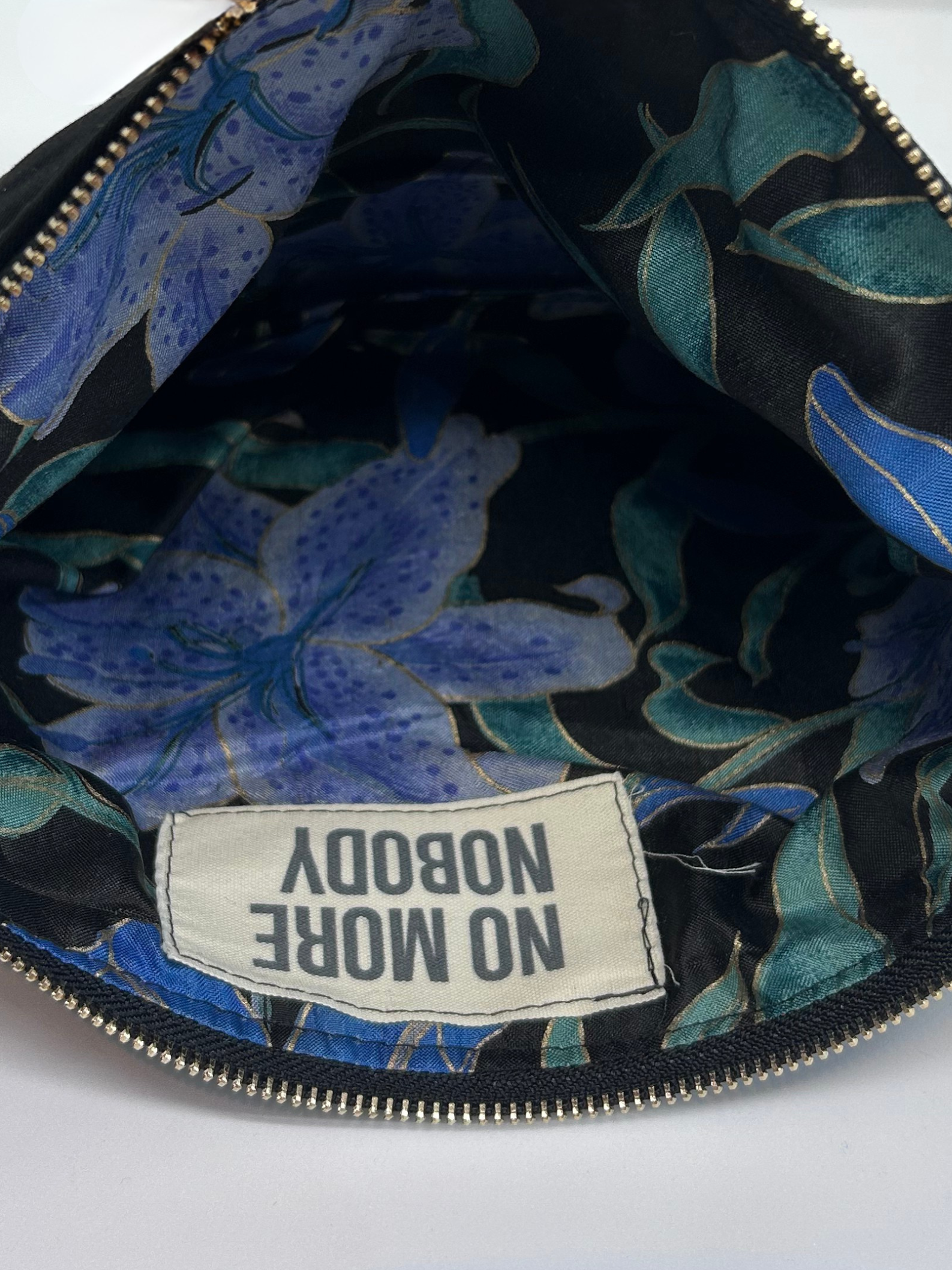 inside of a bag with a floral-patterned lining and a 'NOBODY NO MORE' label on a white background
