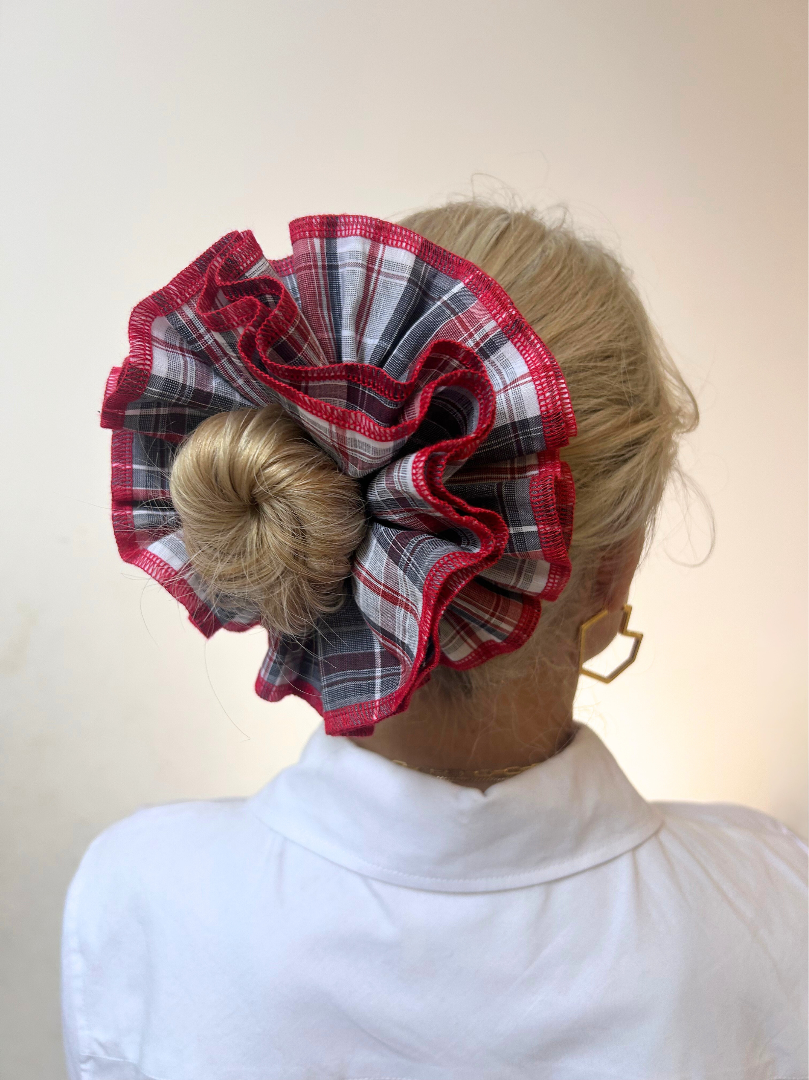 Person wearing a red and black plaid hair bun cover against a plain background