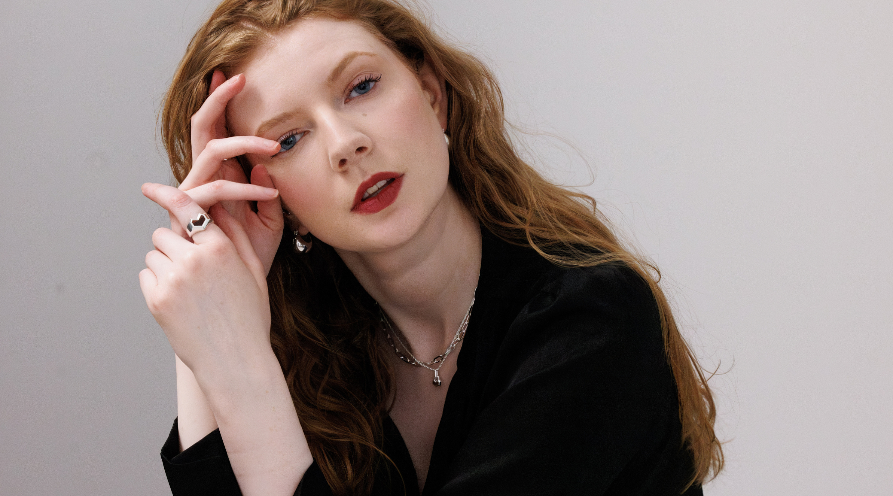 red head woman wearing silver jewellery and a black top