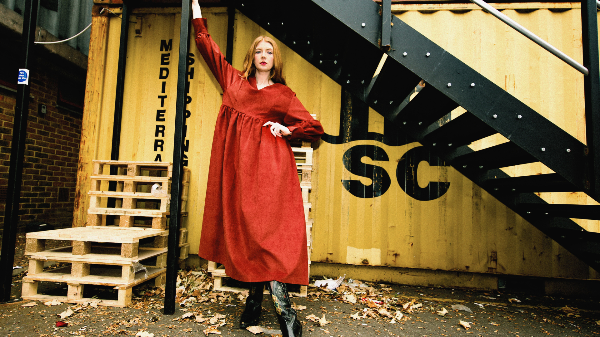 woman wearing a red dress against a staircase in the industrial location