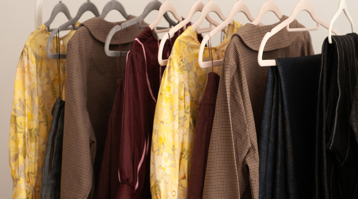 clothes rail with yellow floral blouses, brown jackets and burgundy tops.