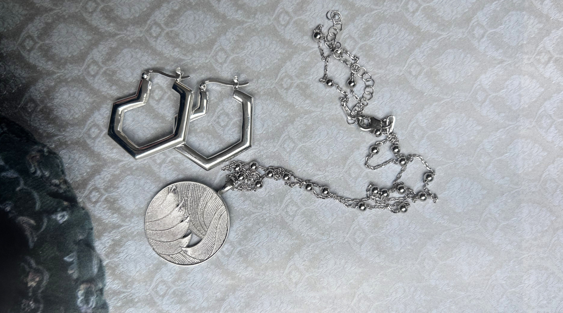 silver earrings and necklace on a vintage inspired ivory fabric