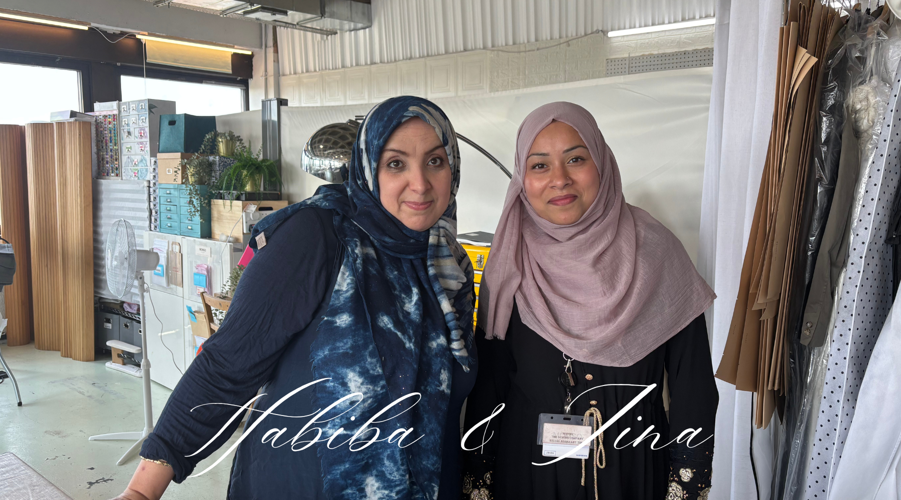 two smiling women wearing a hijab against a workshop background