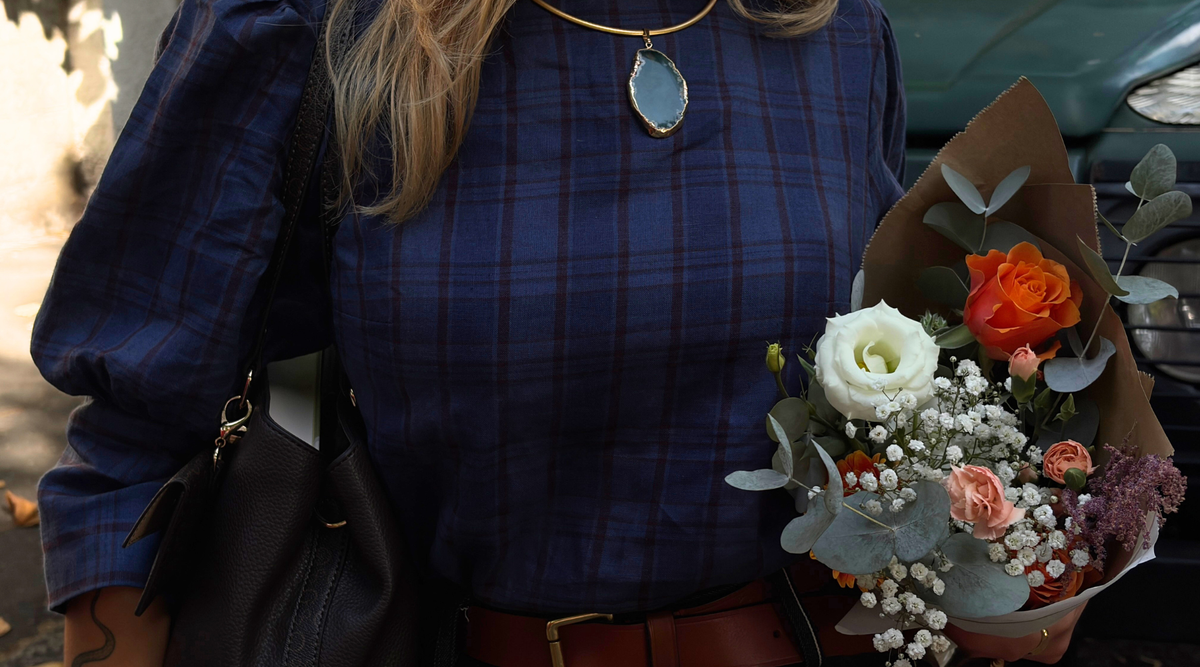 close up of a woman wearing a navy plait top holding a bunch of flowers