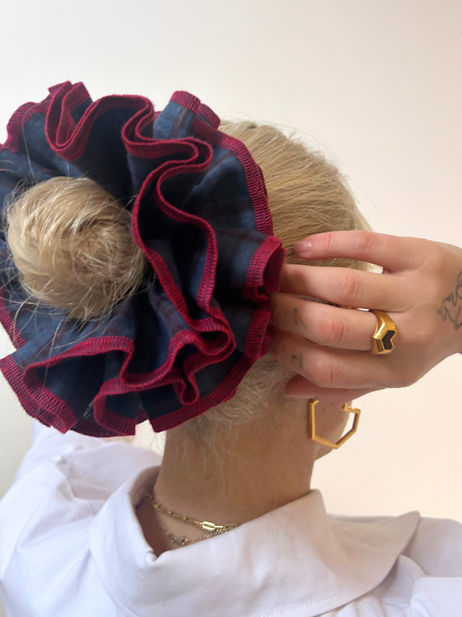 Person wearing a blue and red hair scrunchie with a plain background