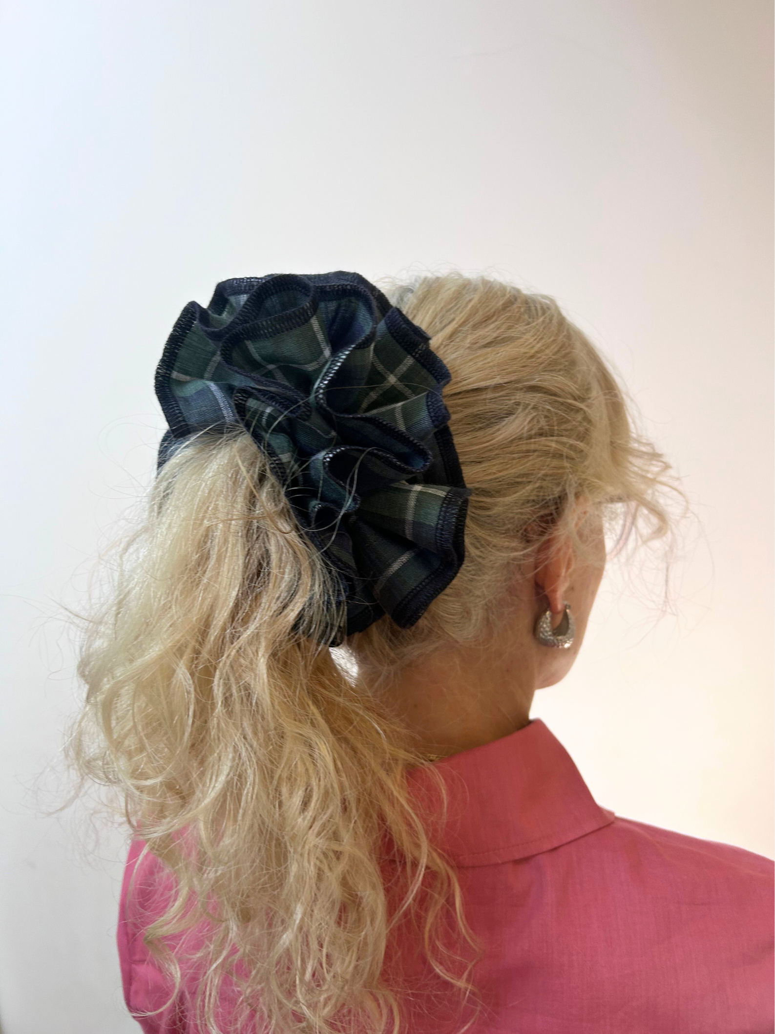 Person with a plaid hair scrunchie in their blonde hair against a white background