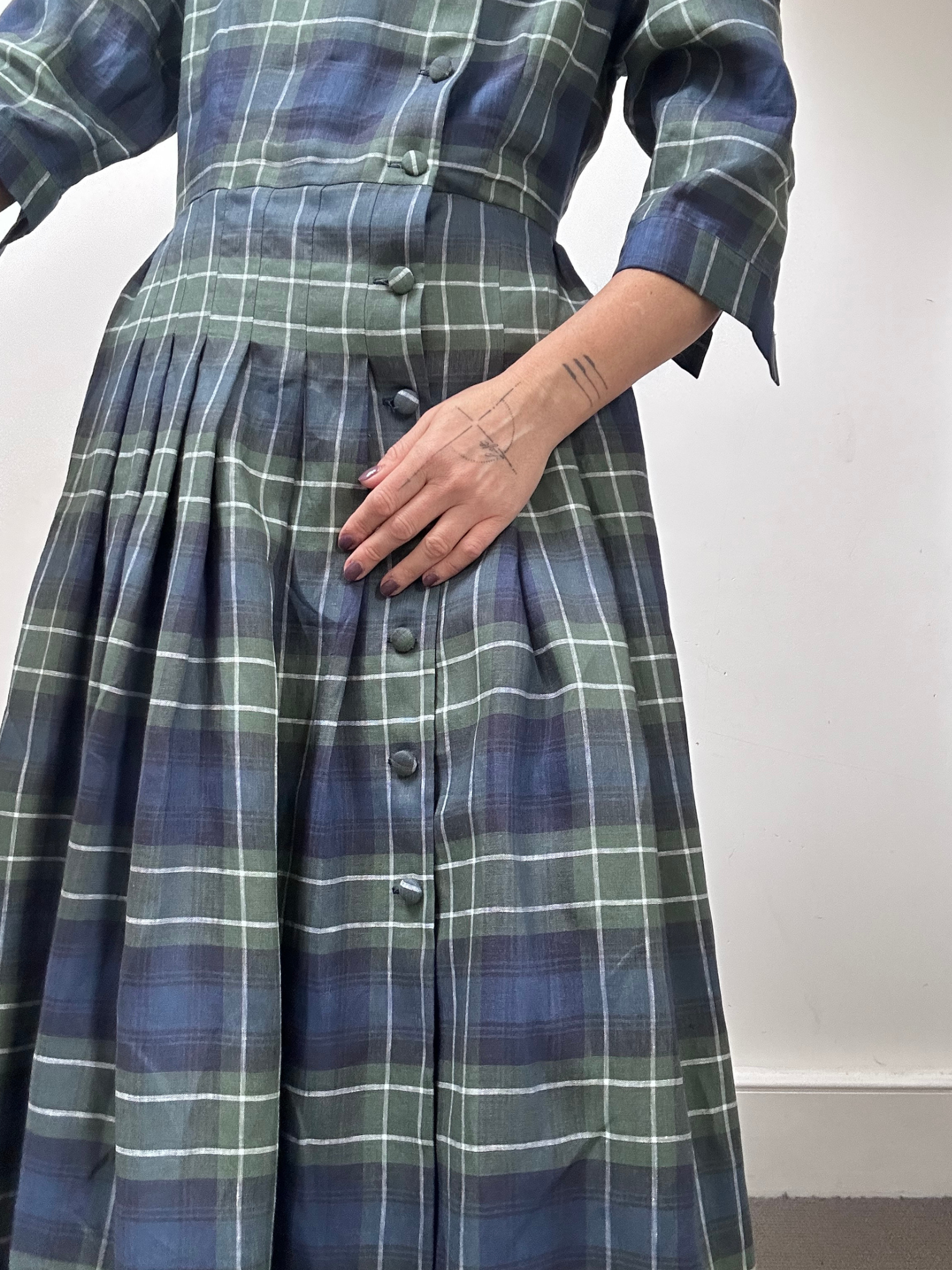 Person wearing a green and blue plaid dress with a white background
