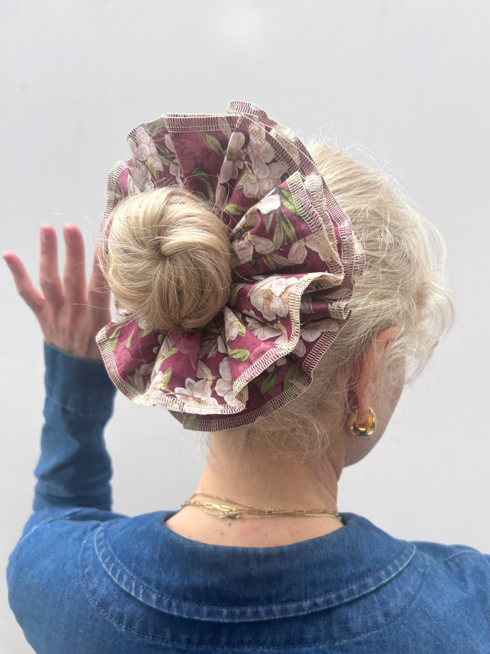 Person wearing a floral hair bun cover against a plain background