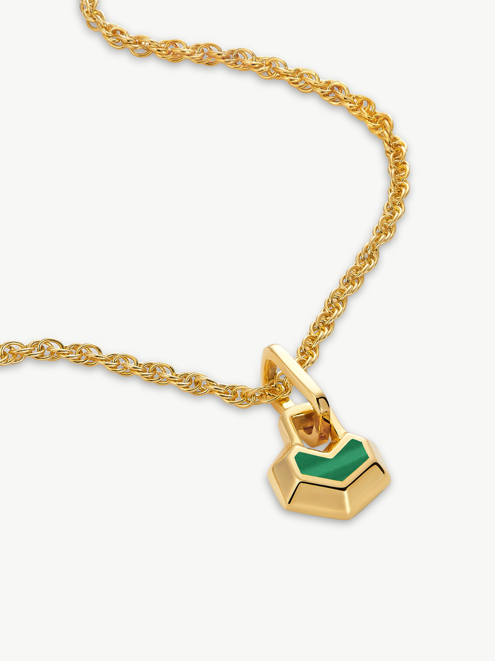 Gold necklace with a green heart pendant on a white background