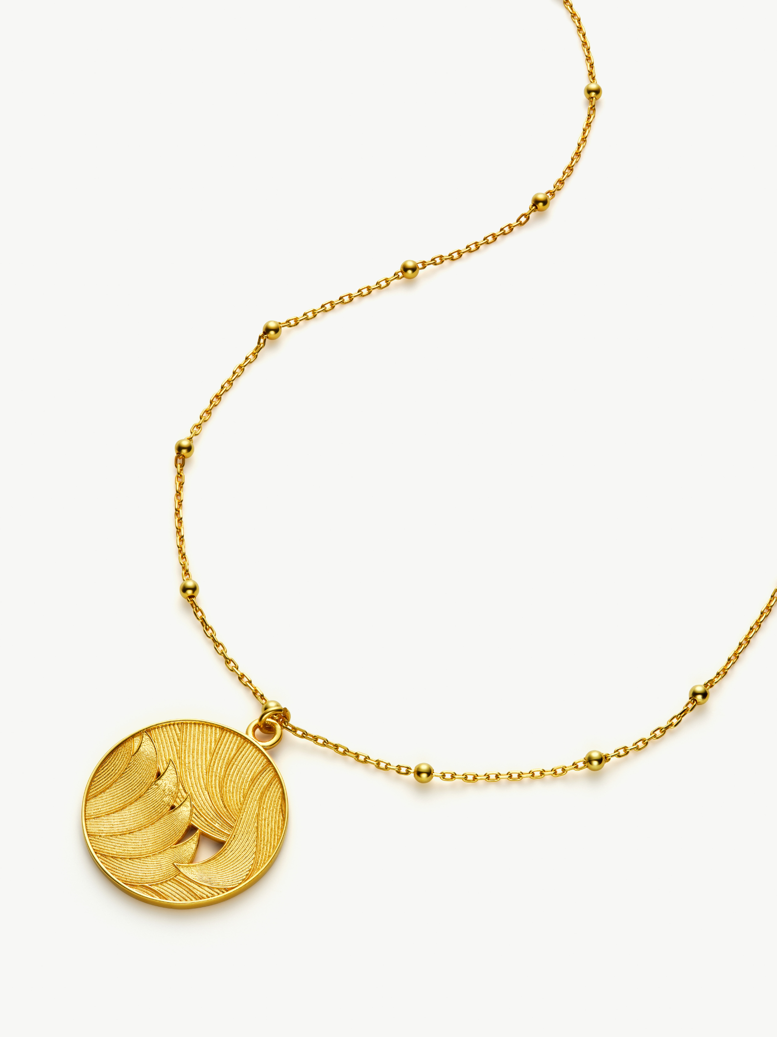 Gold necklace with a round pendant on a white background