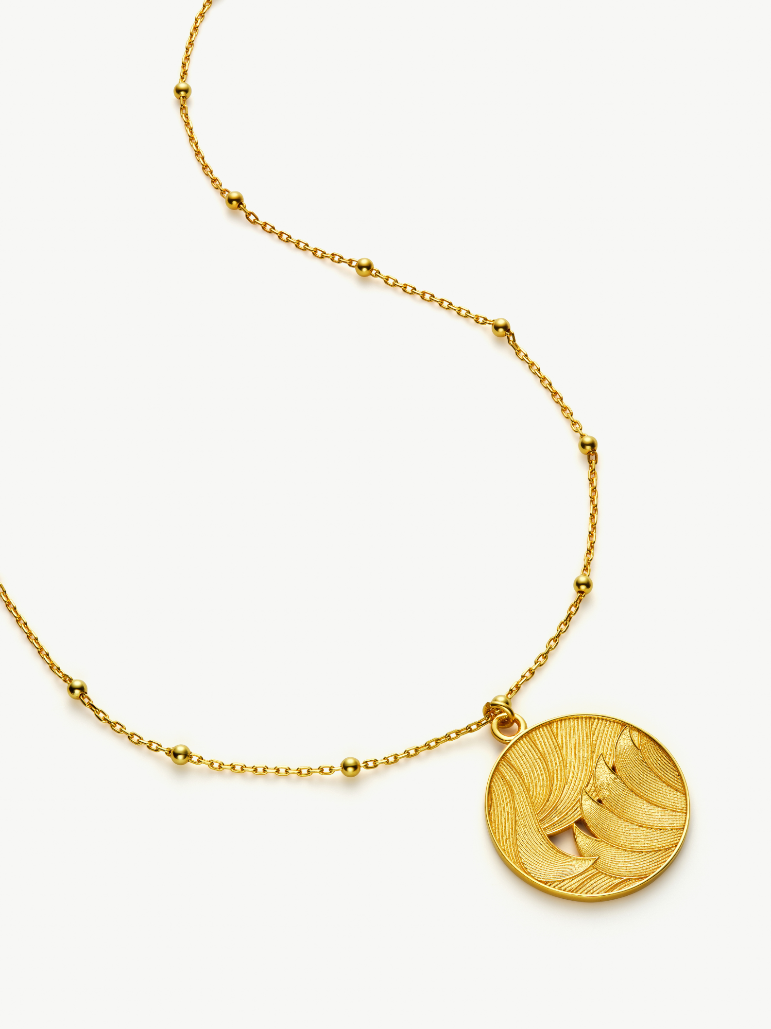 Gold necklace with a round pendant on a white background