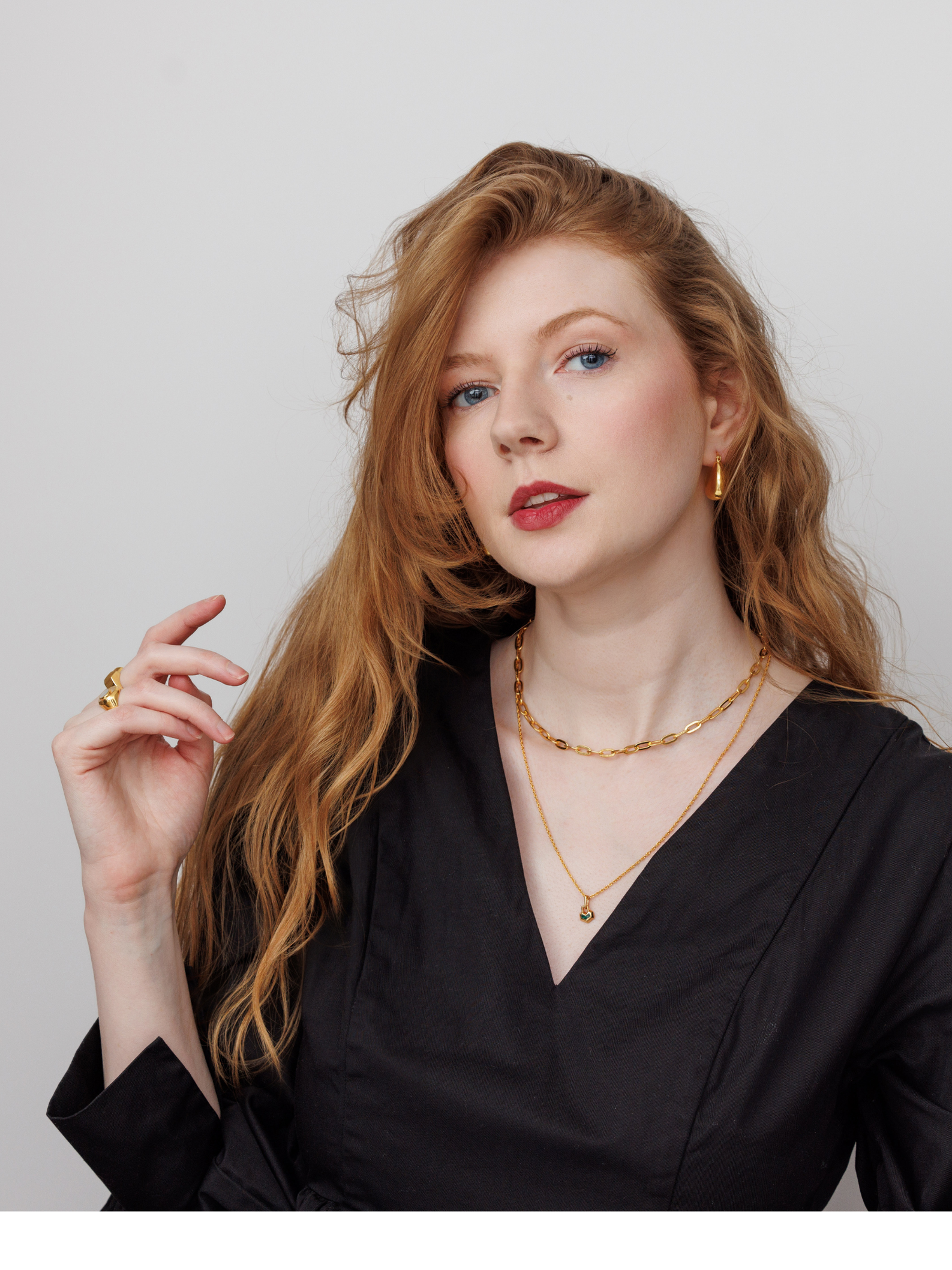 Woman wearing gold jewelry against a plain background