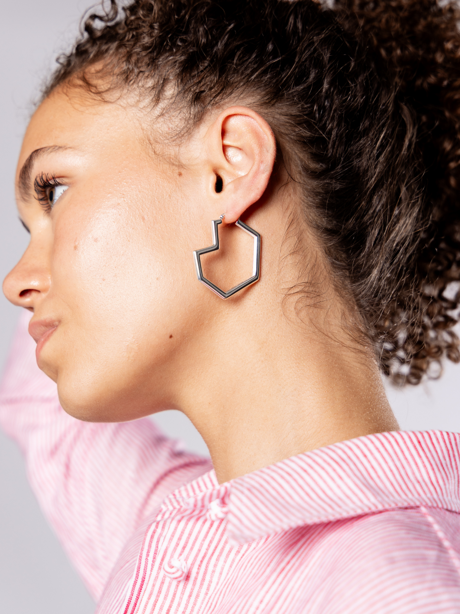 Woman wearing a unique heart hoop silver earring with a red shirt