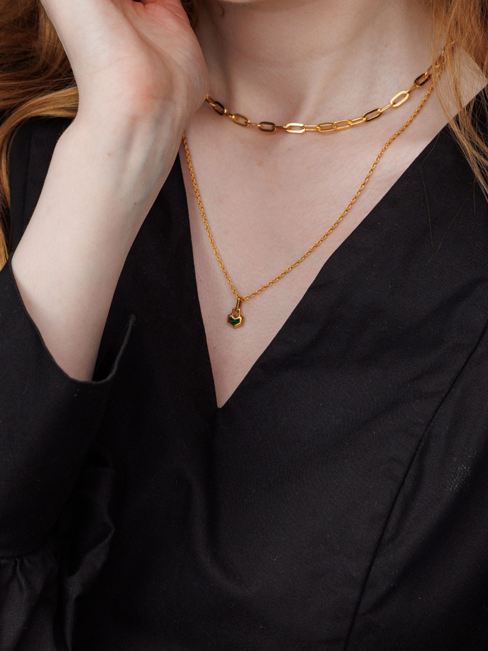 Person wearing two gold necklaces with a black top