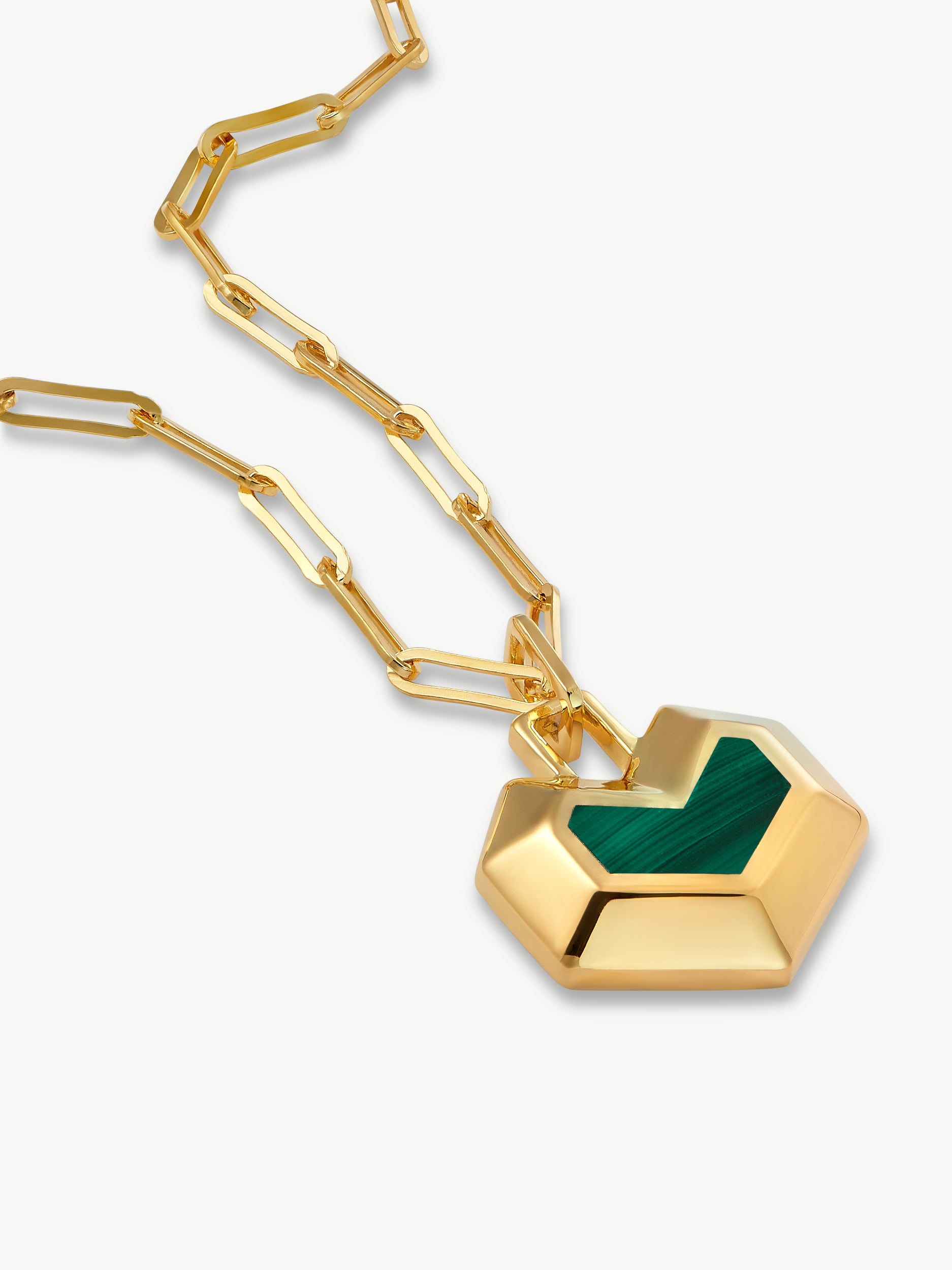 Gold necklace with a green heart pendant on a white background