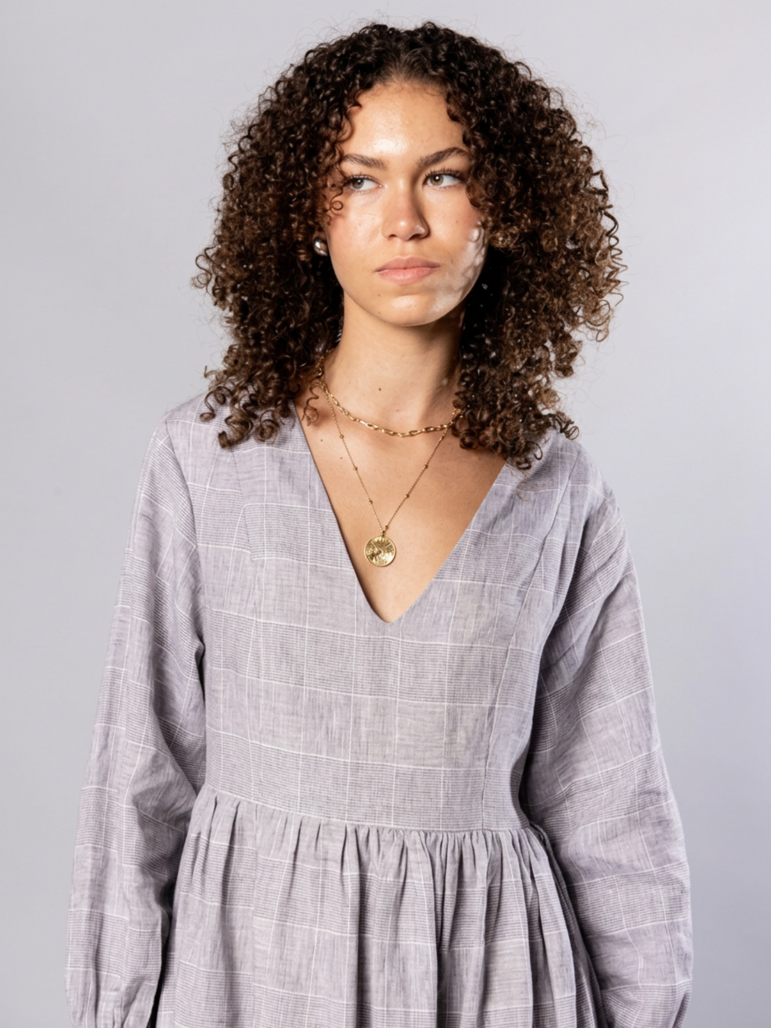 Woman wearing a light gray dress with a plain background